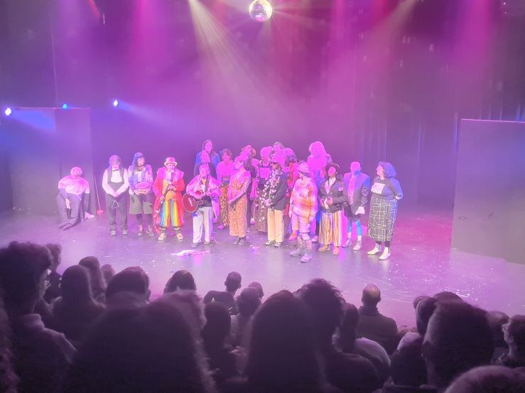 A photo of the cast of Feminist Clown Posse on stage taking their bows, taken from the back of the audience